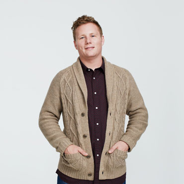 Man in beige cardigan smiling, hands in pockets
