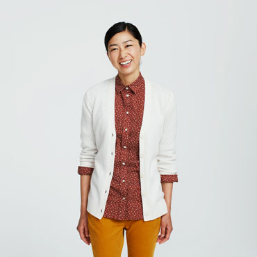 Smiling woman in white cardigan and mustard pants